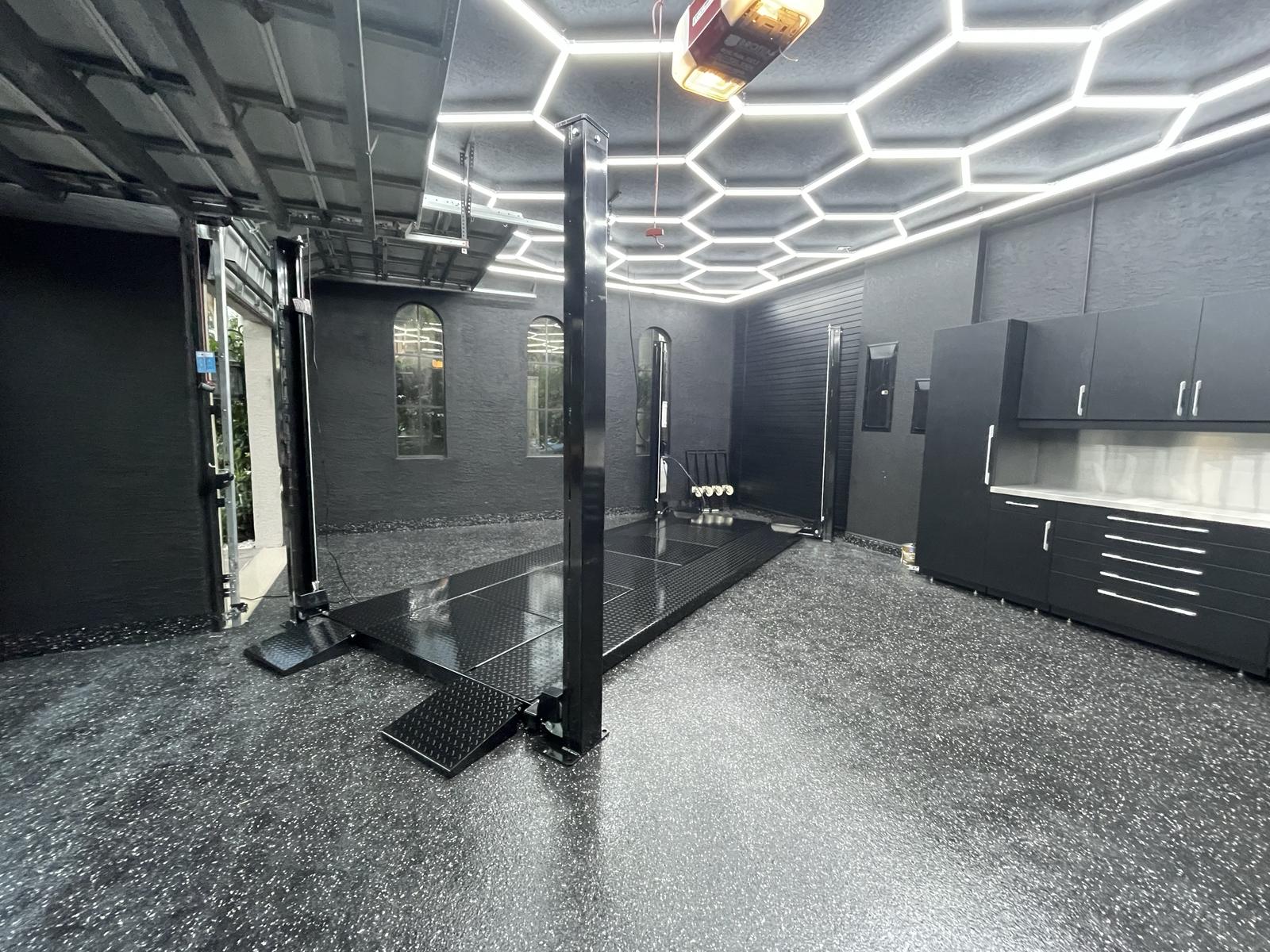 A STAK four-post lift lowered in a home garage, platform and drive-on ramp at floor level